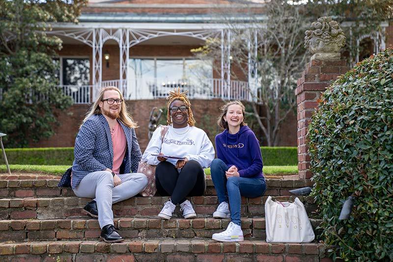 Three Converse students sit on campus.